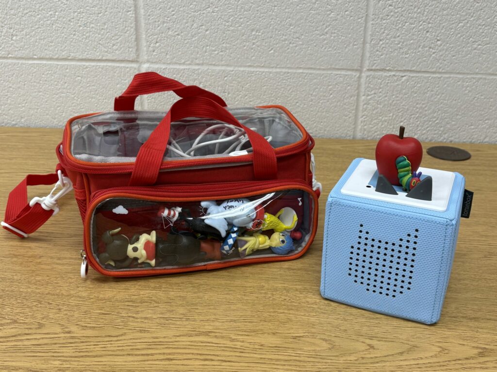 A kit consisting of a red and clear bag as well as a white and orange block with The Very Hungry Caterpillar on top.