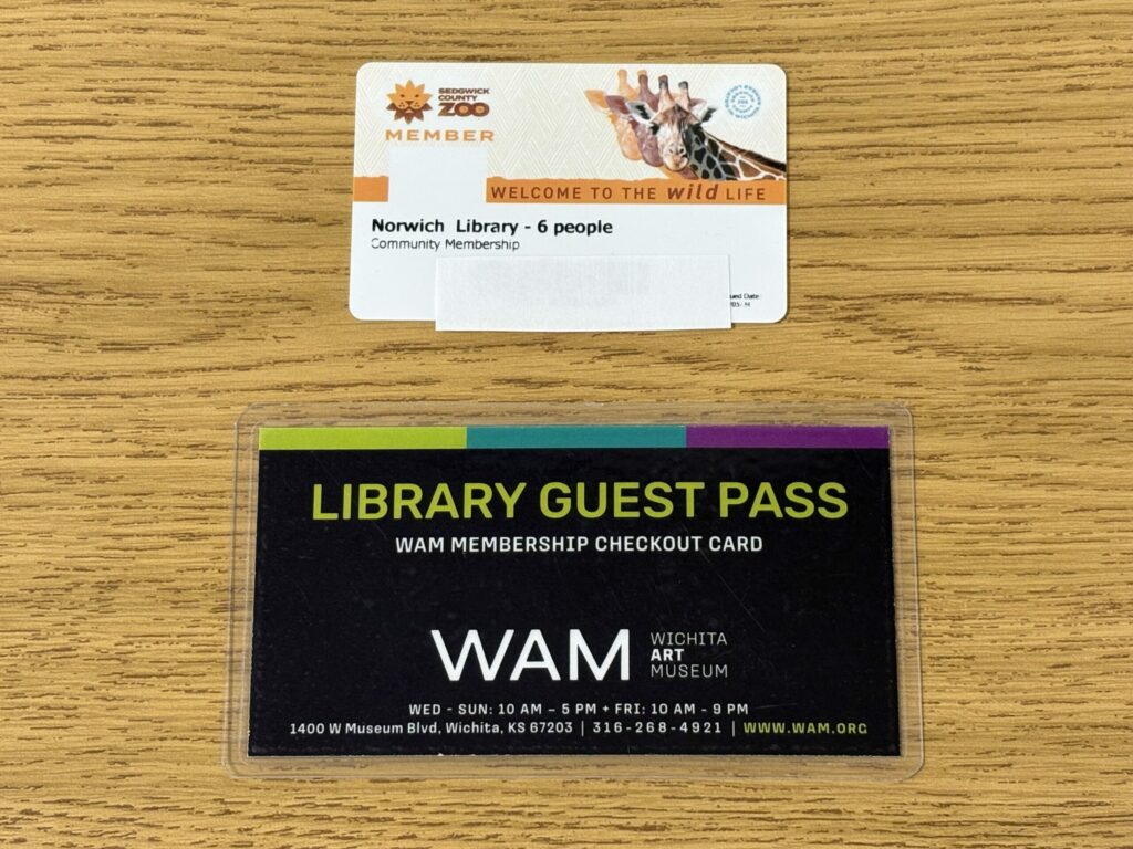 A white zoo card guest pass with a giraffe on it, allowing up to 6 people to visit the Sedgwick County Zoo. A black library guest pass to the Wichita Art Museum.